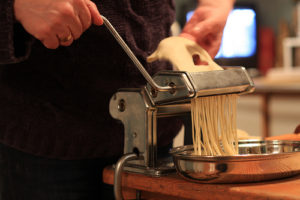 person making pasta using a pasta maker