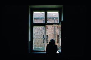 person looking out a window in a dark room
