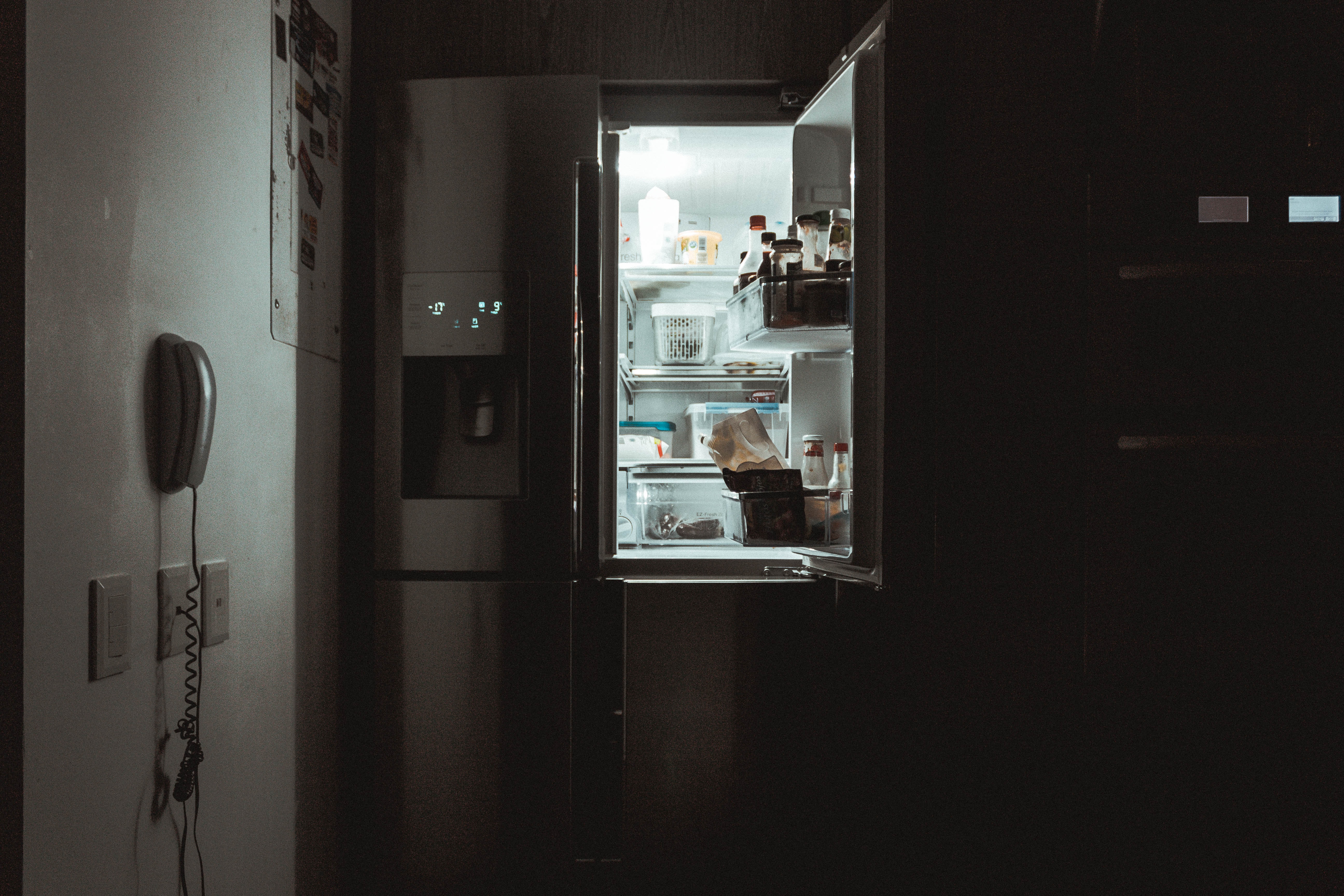 Open refrigerator door in a dark kitchen