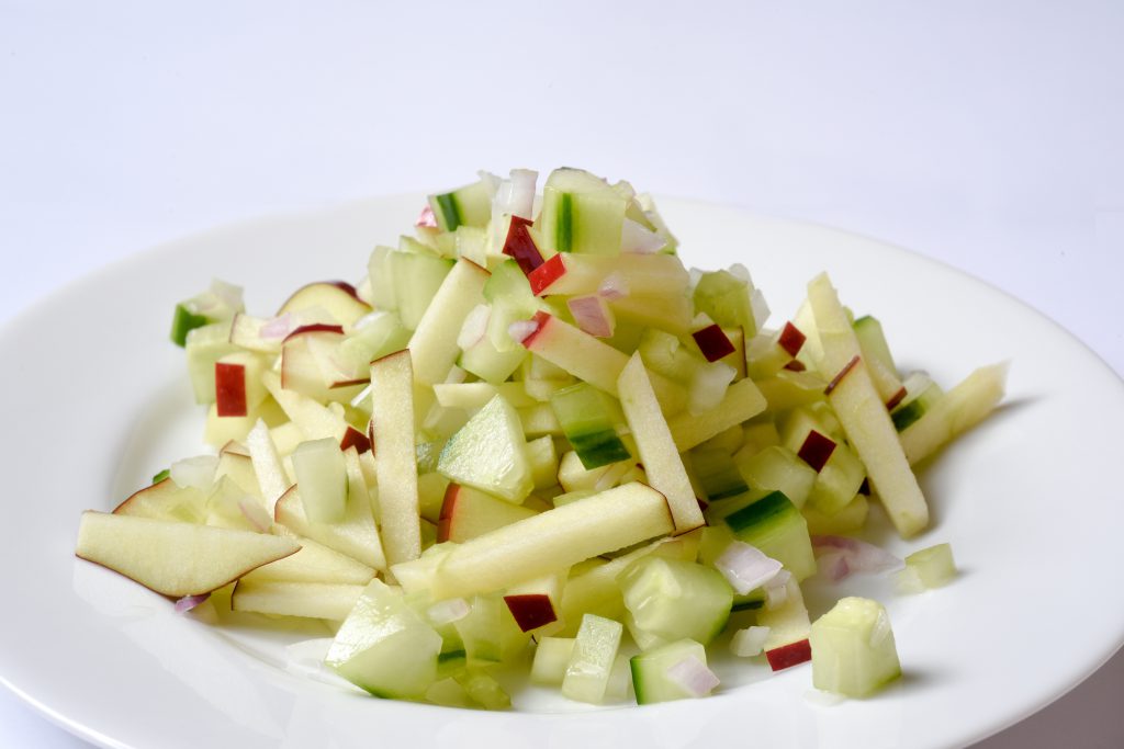 chopped apple, cucumber, and red onion slaw on a white plate 