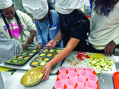 A group of girls sit ingredients for baking in muffin tins.